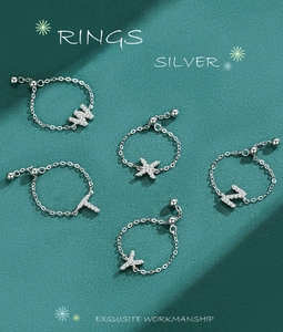 Macro detail of adjustable S925 silver chain rings with sparkling zircon initial letters