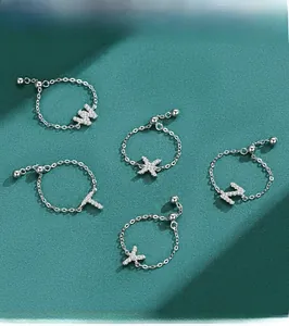 Close-up of S925 sterling silver chain rings with sparkling zircon pavé letters