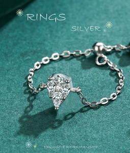 Macro shot of S925 sterling silver chain ring with teardrop zircon on green background