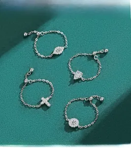 Macro detail of adjustable S925 silver chain rings with pavé cross and evil eye charms