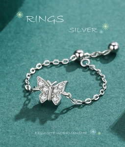 Detailed view of silver butterfly chain ring with zircons on dark green texture