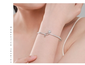 Close-up of s925 sterling silver bangle with knotted design and pavé diamond orb on wrist