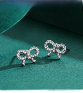 Close-up of elegant S925 silver bow stud earrings with micro-set zircon on green velvet