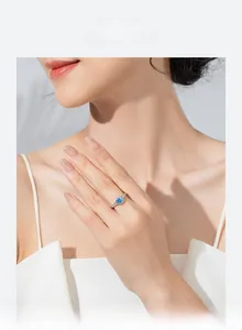 Primo piano dell'anello in argento s925 con zircone blu rotondo e pavé di pietre su una modella