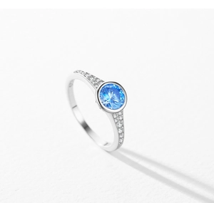 Macro di un anello in argento S925 con zircone blu a taglio rotondo e castone lucido