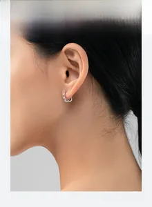 Close-up of polished silver heart-shaped hoop earring worn on model's ear