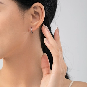 Close-up of woman wearing s925 silver hoop earrings with textured diamond patterns