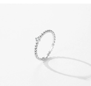 Detailed close-up of a silver beaded ring with micro-set zircon in a minimalist style
