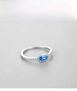 Gros plan d'une bague en argent S925 avec pierre bleue ovale et petits diamants fins