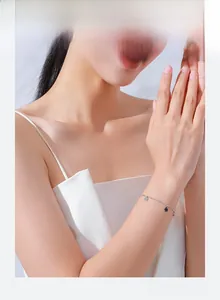 Silver bead bracelet with black clover charm shown on a woman wearing a white top