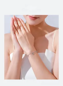 Detail shot of a s925 silver heart charm bracelet worn on a woman's wrist with soft lighting