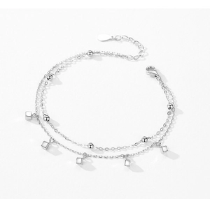Macro shot of silver double-layered chain bracelet with cube pendants and lobster clasp