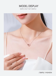 Close-up of minimalist s925 sterling silver interlocking double ring heart necklace on model