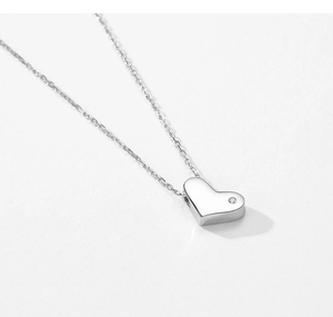 Macro detail of a S925 sterling silver heart necklace featuring a single micro-inlaid diamond