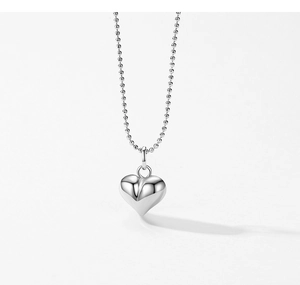 Vue macro du pendentif coeur en argent S925 poli et de la fine chaîne à billes métal