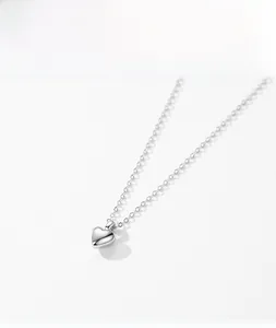Macro detail of a polished S925 sterling silver heart pendant necklace on white background