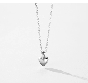 Detailed close-up of a polished S925 sterling silver heart pendant with fine cross chain