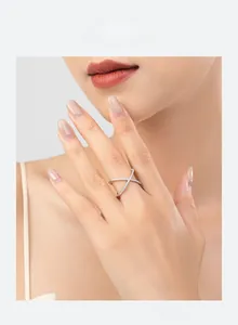 Detail shot of a silver s925 X-shaped crossover ring with sparkling zirconia on model's finger