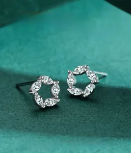 Close-up of S925 silver flower earrings with marquise-cut zircons on a green display
