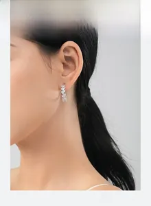 Macro side view of a model wearing sparkling pear-cut cubic zirconia drop earrings in S925 silver