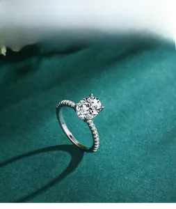 Macro shot of oval cut diamond ring with pavé accents on a luxury green texture