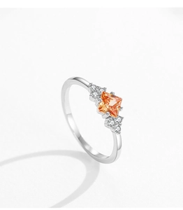 Close-up of square champagne zircon ring with side diamonds on silver band