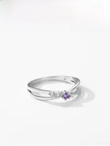 Détail macro de la bague en argent S925 avec zircon violet et design à bande croisée