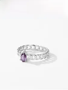 Gros plan sur bague en chaîne argentée ornée d'une pierre violette en forme de poire