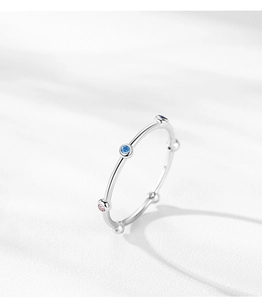 Macro detail of slim S925 silver ring with colorful zircon stones on white texture