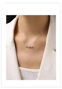 Macro shot of silver necklace with five colorful cubic zirconia stones on model
