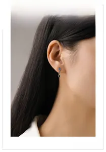 Close-up of model wearing geometric silver earrings with colorful zircon gemstones