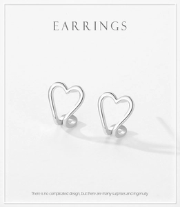 Macro shot of minimalist hollow heart-shaped S925 silver earrings on a beige background