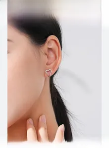 Close-up of minimalist S925 sterling silver hollow heart stud earring worn by a model