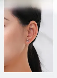 Close-up of elegant hollow butterfly stud earrings in silver on a female ear