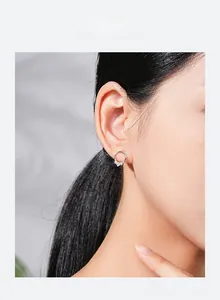 Close-up of a silver hoop earring featuring three cubic zirconia on a model's ear