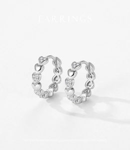Détail macro de créoles en argent sterling S925 avec motif cœur pavé et finition argentée