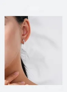 Close-up of minimalist S925 sterling silver hoop earring with a sparkling zircon on model