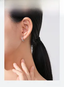 Gros plan de boucles d'oreilles créoles coeur en argent S925 avec zircons sur l'oreille