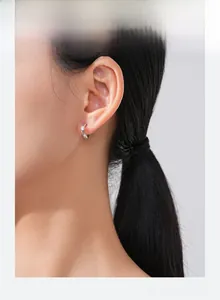 Close-up of S925 silver hoop earring with twisted wave design and round zircon on model