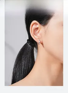 Close-up of small silver geometric hoop earring with micro-inlay details worn by model