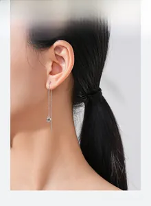 Detail of S925 sterling silver long tassel heart earrings on model showing dangle length