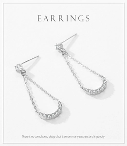 Macro shot of silver tassel earrings with geometric zirconia stones on white background