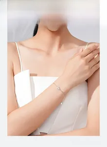 Detailed view of teardrop pendant bracelet with sparkling stones on model's wrist