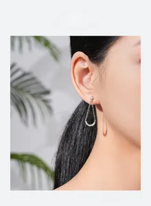 Detail view of silver S925 tassel earrings with geometric zircon on an Asian model