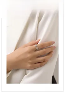 Detail of silver leaf open ring with pavé crystals worn on a model in a white blazer