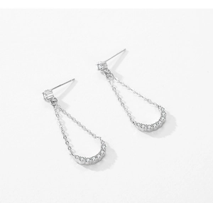 Detailed view of silver tassel earrings with geometric curved bars and zircon stones