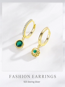 Détails macro des boucles d'oreilles en argent doré avec zircon vert émeraude