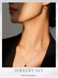 Photo portée d'un ensemble de bijoux en or rose avec collier et boucles d'oreilles rouges