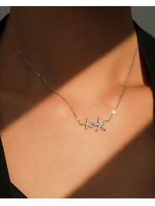 Macro shot of silver starfish pendant necklace with zircons on model neck in soft light