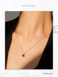 Détail du collier en or rose avec une pierre rouge ronde et des accents de diamants